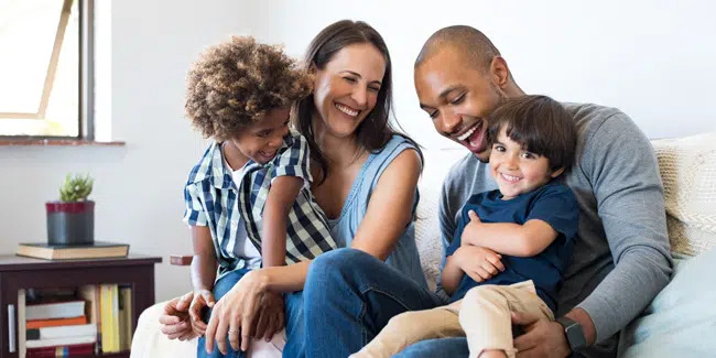 Smiling family of four relaxing together on a couch — family dentist in Richardson, TX